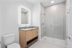 A modern bathroom with a toilet, vanity, and a glass-enclosed shower. - Modern Huntsville Stay | 1 Unit | Near Mid City Drive (Huntsville)