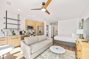 A modern hotel room with a kitchenette, a sofa, a bed, and a ceiling fan. - Modern Huntsville Stay | 1 Unit | Near Mid City Drive (Huntsville)