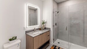Ein modernes Badezimmer mit Waschtisch, großem Spiegel, Dusche und Toilette.