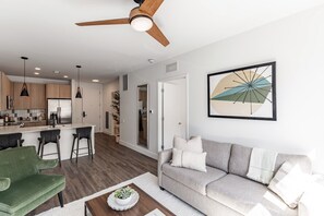 A modern living room with a grey sofa, a green armchair, and a coffee table with a plant. - Modern Huntsville Stay | 1 Unit | Near Mid City Drive (Huntsville)