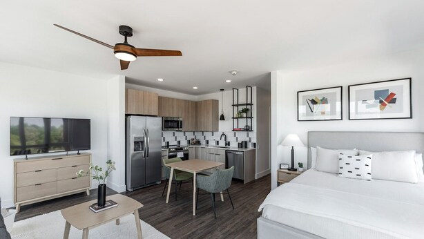 Una habitación de hotel moderna con cama, escritorio, kitchenette y televisor.