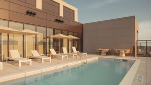 A rooftop pool area with lounge chairs and umbrellas, a pool with a clear blue water, and a modern building facade. - Modern Atlanta Retreat | Deluxe City View room | Near Midtown Hotspots (Atlanta)