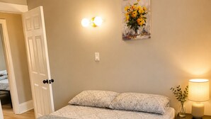 A bedroom with a double bed, a bedside table with a lamp, and a wall-mounted light fixture.
