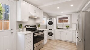A modern kitchen with white cabinetry, stainless steel appliances, and a wooden floor.