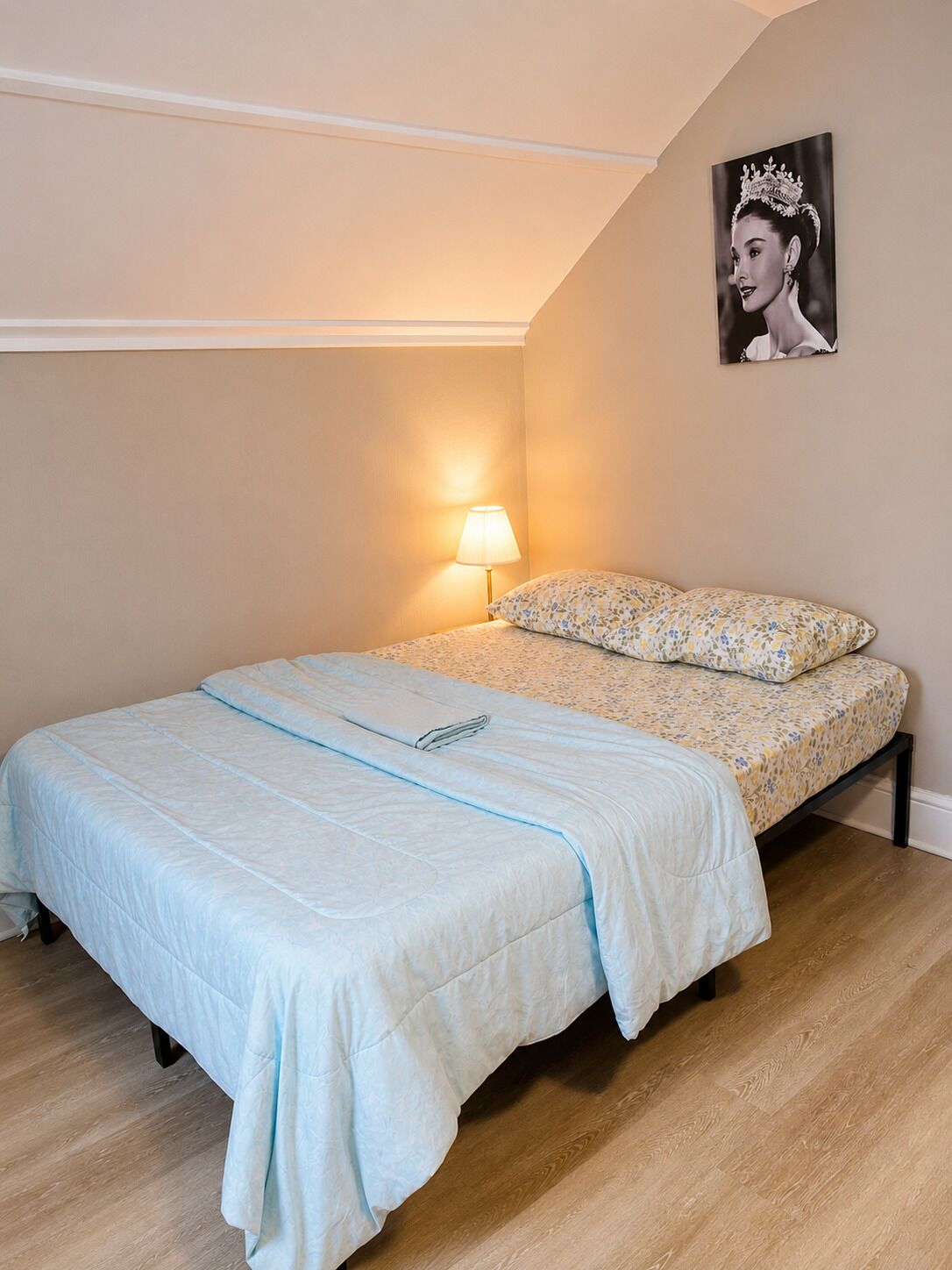A bedroom with a bed, a nightstand, a lamp, and a framed picture on the wall.