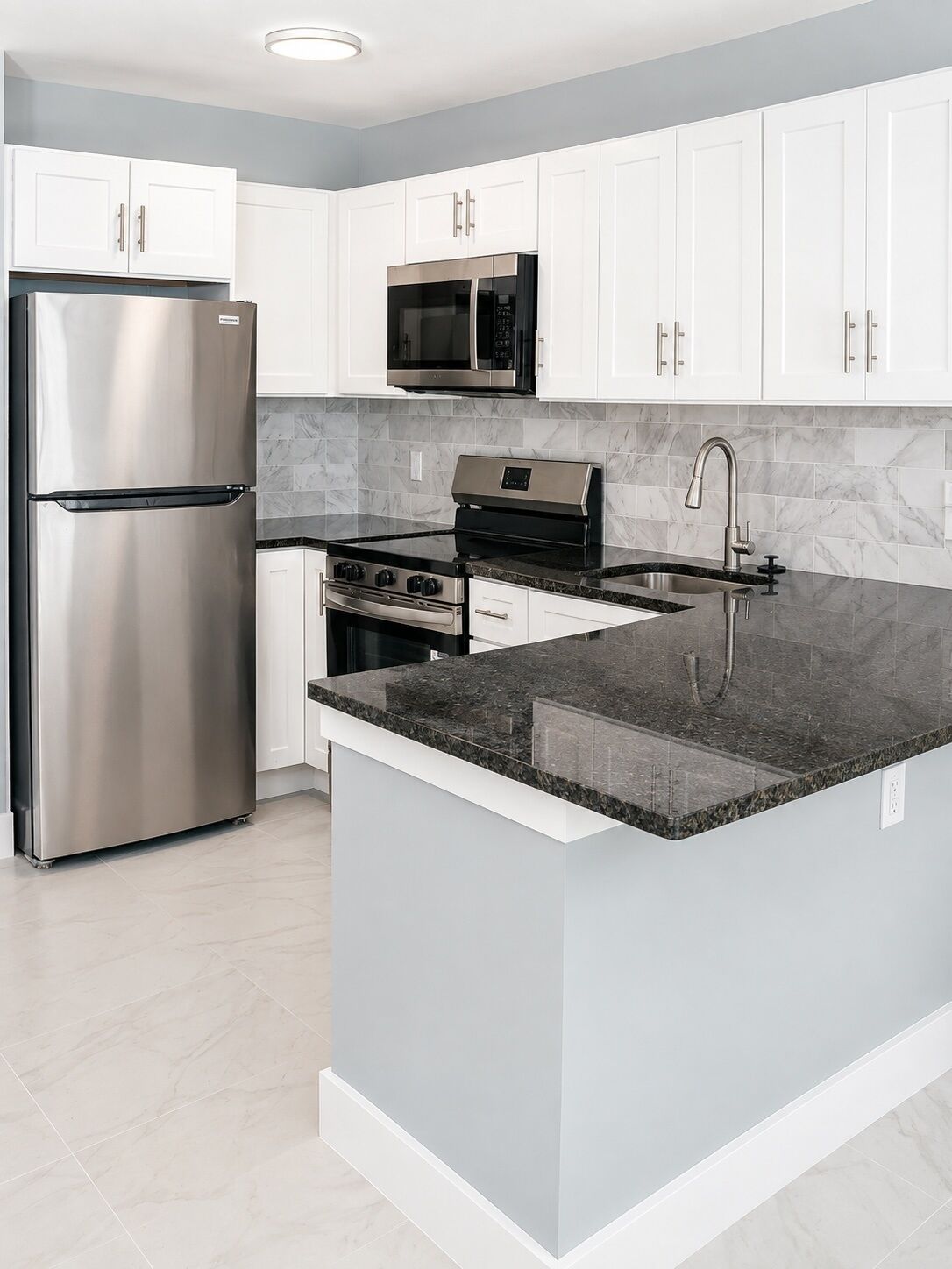 A modern kitchen with white cabinets, stainless steel appliances, a granite countertop, and a built-in microwave.