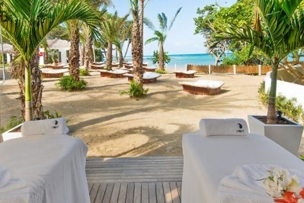 Een terras aan het strand met ligbedden en een houten dek.