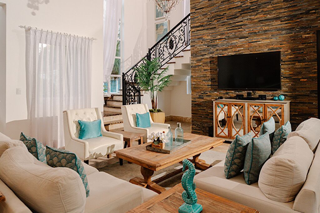 A living room with a sofa set, a coffee table, a TV, and a staircase with a railing.