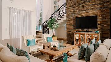 A living room with a sofa set, a coffee table, a TV, and a staircase with a railing.