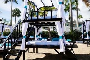 A beachside hotel with multiple rooms, each featuring a bed with a canopy and a view of the palm trees. - 7BR VIP Villa with Private Pool, Gold band, Chef & Golf Cart, Puerto Plata, DR (Puerto Plata)