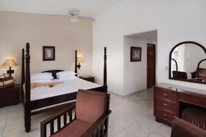 Een slaapkamer met een hemelbed, nachtlampjes, een dressoir en een spiegel.