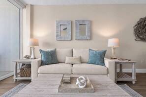 Ein neutral gestaltetes Wohnzimmer mit einer Couch, zwei Beistelltischen und einer Wanddekoration.