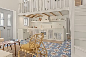 Een kamer met een eethoek, een keuken met witte kastjes en een vloer met een patroon.