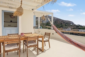 Une terrasse avec une table et des chaises en bois, un hamac et une vue sur un paysage montagneux.