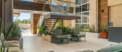 A modern indoor area with a staircase, seating, and potted plants.