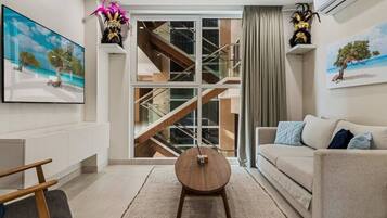 Un salon moderne avec un canapé, une table basse et un escalier menant à l’étage supérieur.