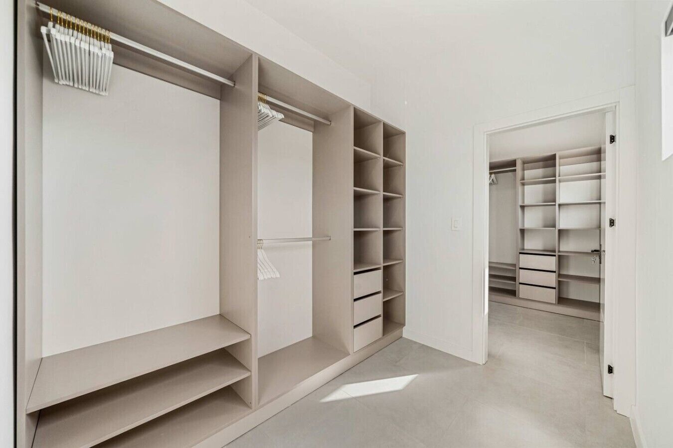 A walk-in closet with open shelving, a hanging rod, and a built-in radiator.