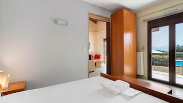 Ein Hotelzimmer mit Bett, Nachttisch, Fenster mit Blick ins Freie und einer Tür zu einem anderen Raum.