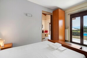 A hotel room with a bed, a nightstand, a window with a view of the outdoors, and a door leading to another room. - Villa 'Ilektra' in Marathiás (Marathiás)