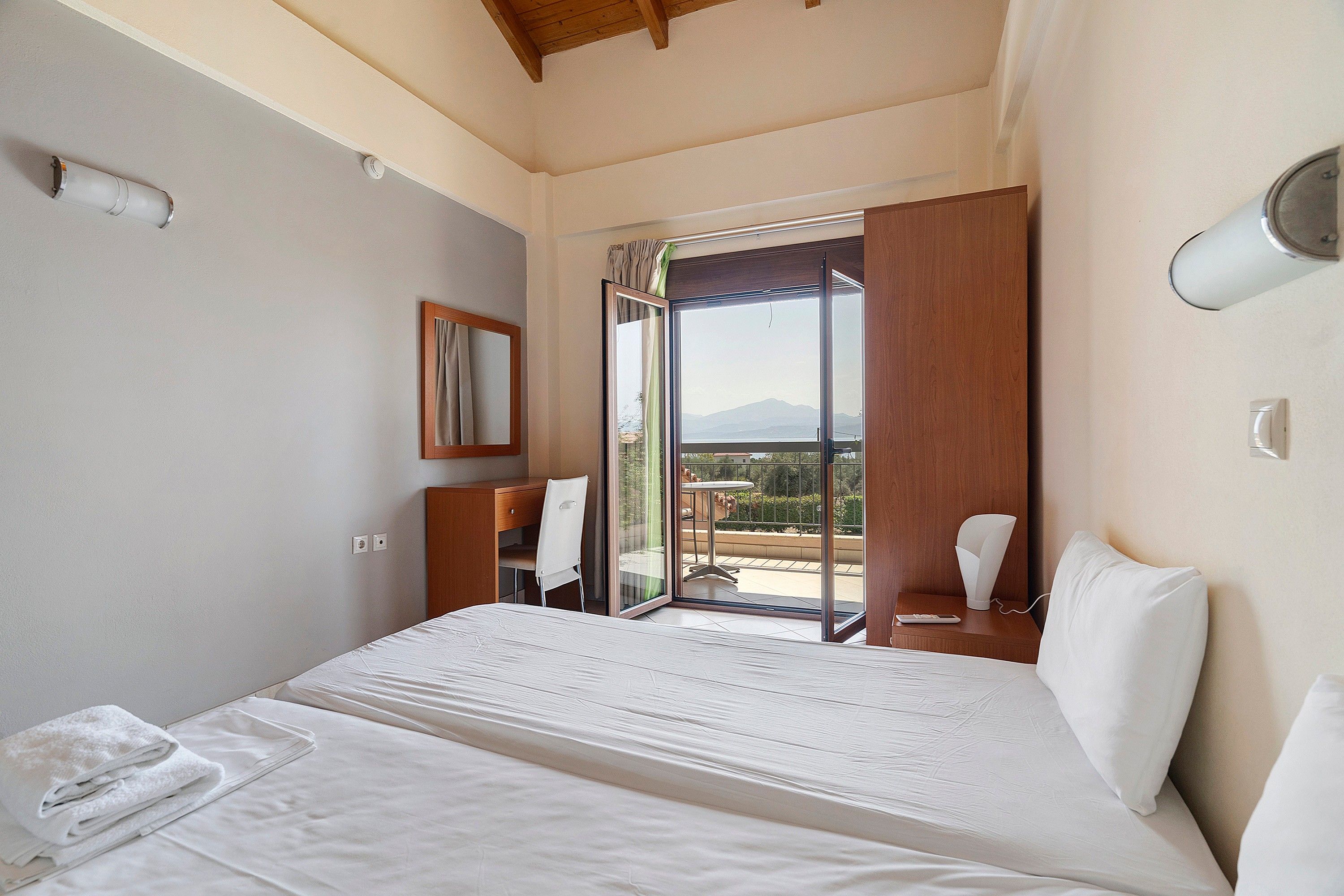 A hotel room with a bed, a desk, a chair, a window with a view, and a bathroom.