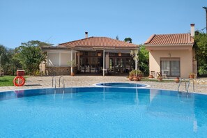 A swimming pool with a lifebuoy, a covered patio area, and a small building with a tiled roof. - Villa 'Ilektra' in Marathiás (Marathiás)