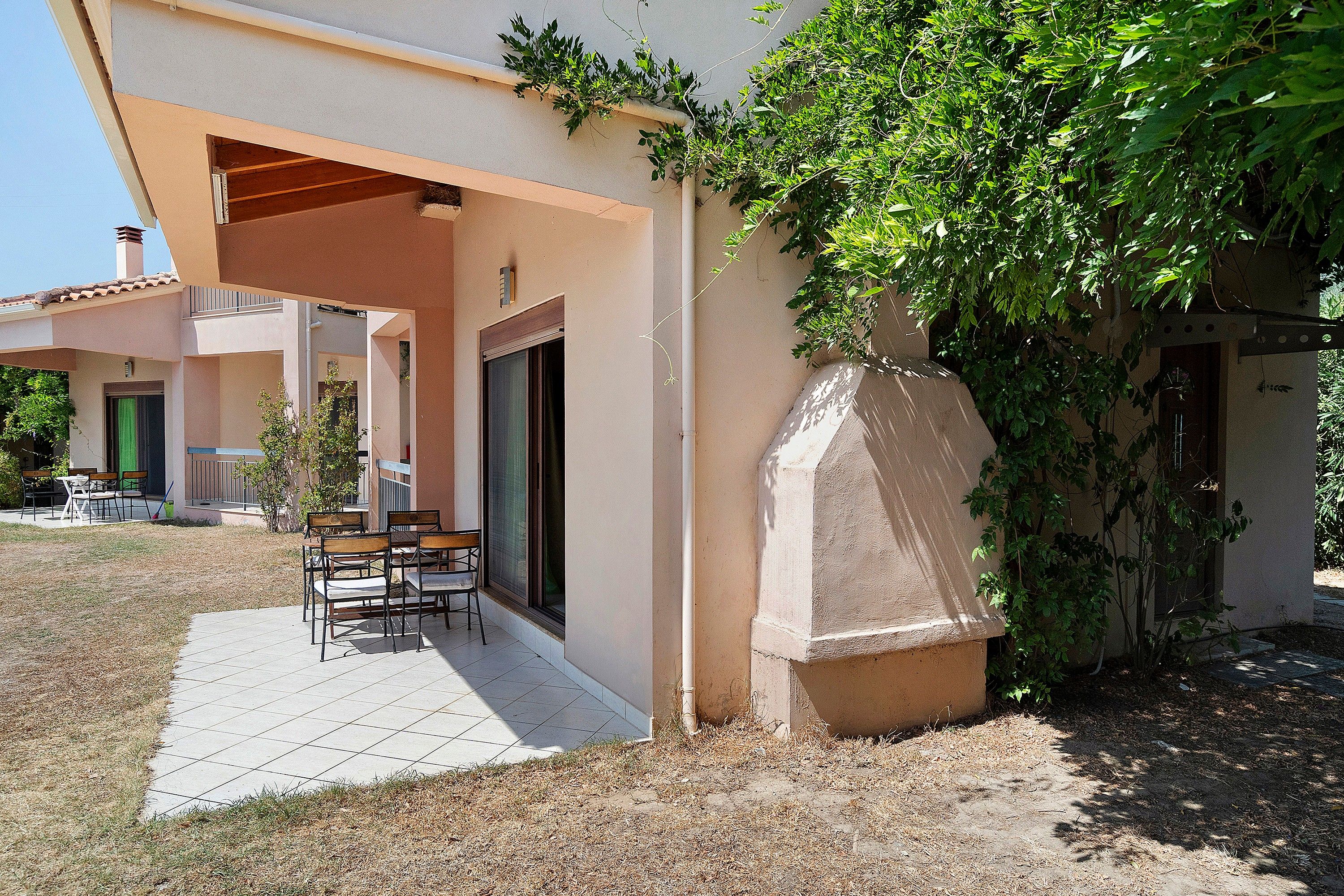 Un edificio con un patio cubierto, mobiliario exterior y una estructura de piedra.