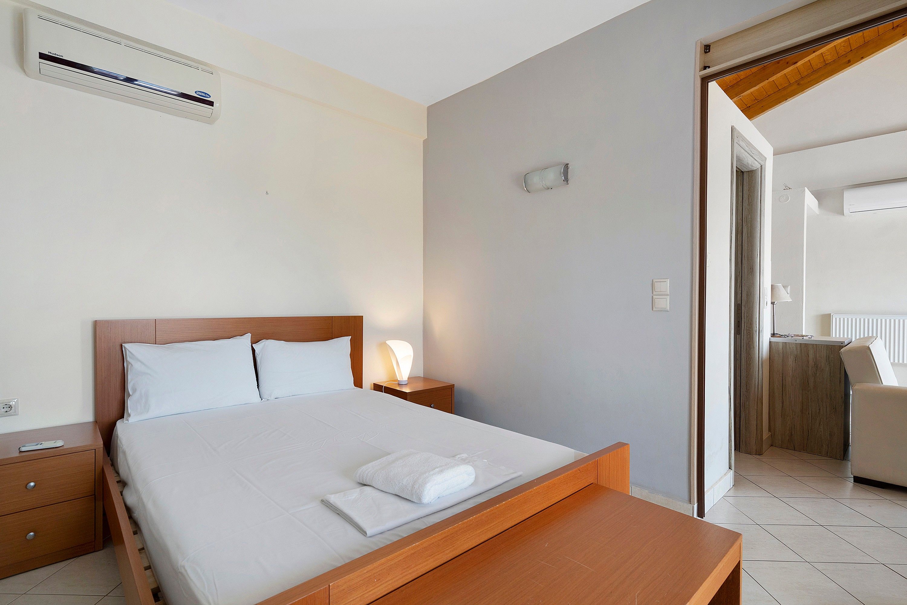 Una habitación de hotel con cama, mesita de noche y aire acondicionado.
