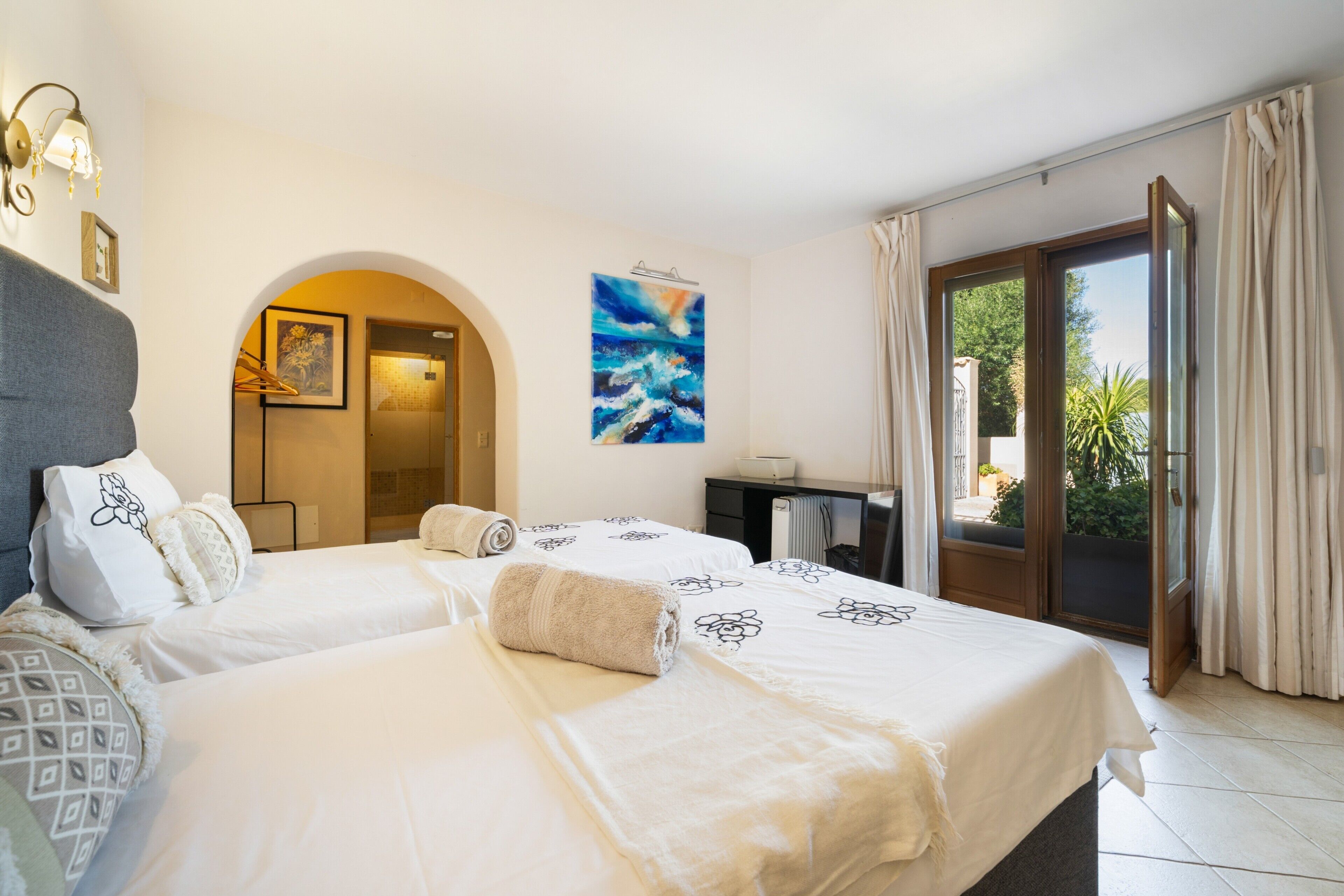 Quarto de hotel com duas camas, um quadro, uma escrivaninha e vista para o exterior.