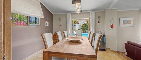 A dining area with a wooden table, chairs, and a view of a swimming pool.