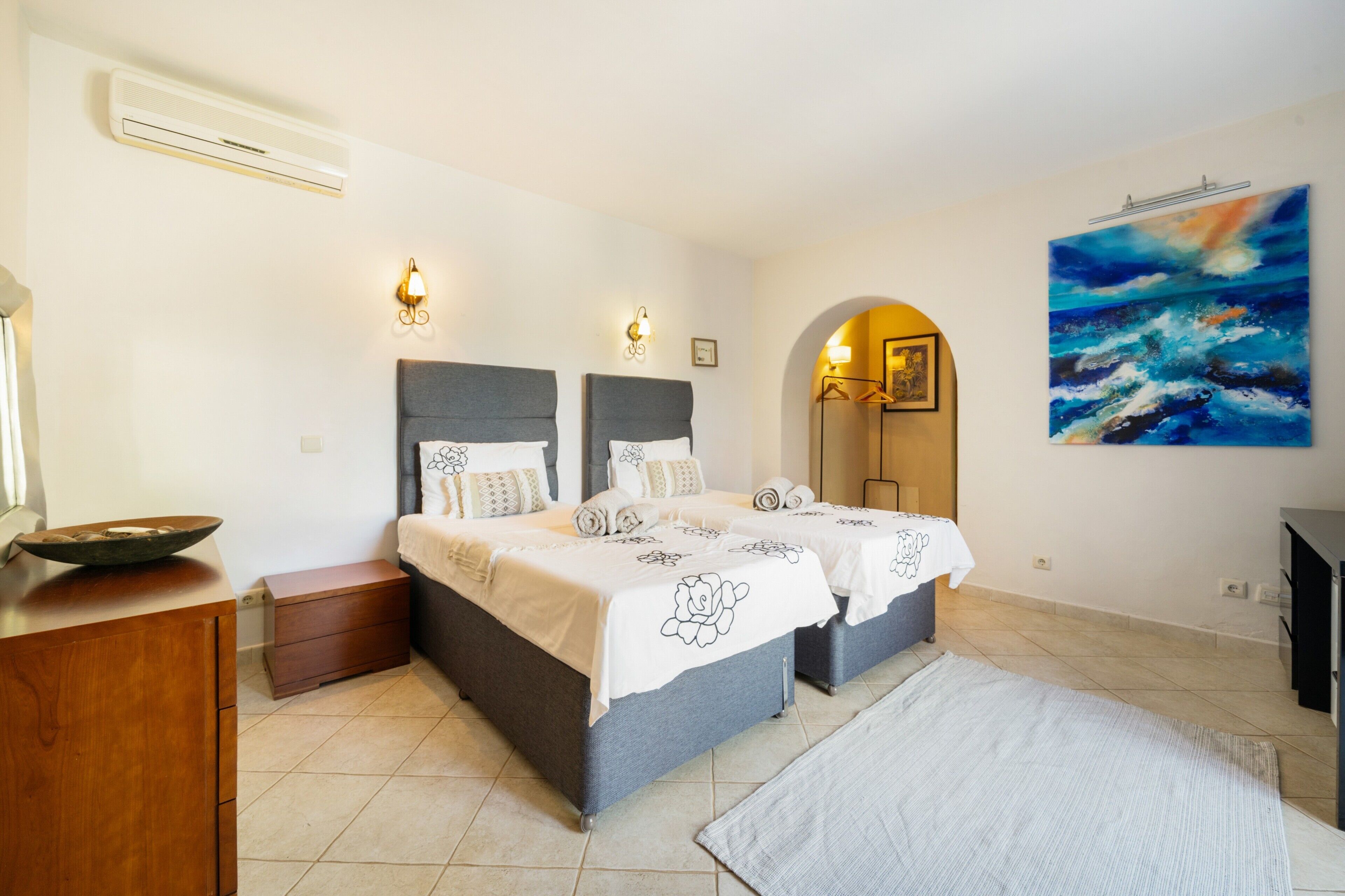 Une chambre d’hôtel avec deux lits, un grand tableau, un miroir et une table de chevet en bois.