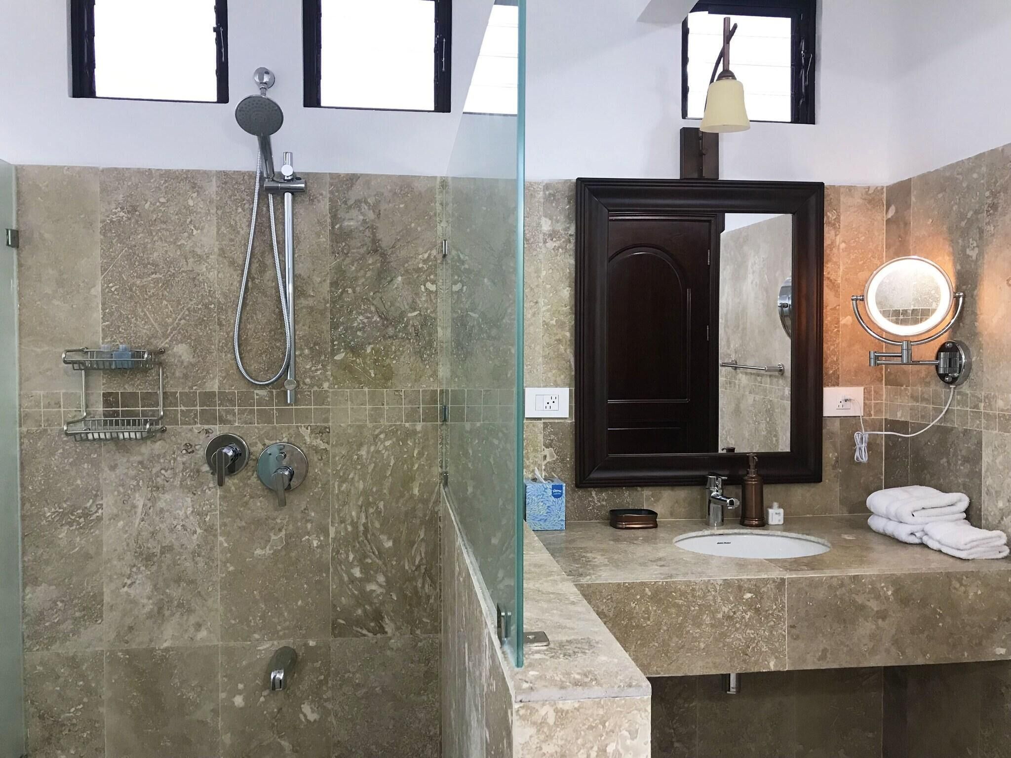 Une salle de bain équipée d’une douche, d’un lavabo, d’un miroir et d’un porte-serviettes.