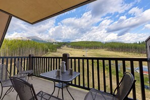 A balcony with a table and chairs, overlooking a forested valley and mountains. - Crystal Peak Lodge 7403 ~ Ski-in/Ski-out ~ NEW LISTING ~ By CoralTree Residences (Breckenridge)