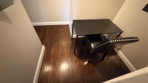 Une pièce d’angle avec un plancher en bois foncé, une petite table noire et un mur blanc.