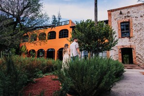 A courtyard with a brick building and a structure with arched windows. - Casa Grande Rio (Rioverde)