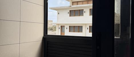 A room with a large window, tiled walls, and a view of a building outside.