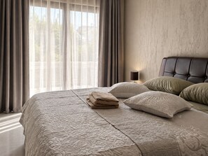 A neatly made bed with a textured bedspread, a bedside lamp, and a headboard. - Tranquil 2-bedroom apartment in delightful Mindelo perfect for relaxing (Mindelo)