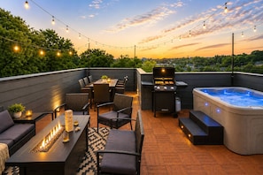 An outdoor patio with a grill, seating area, and a hot tub.