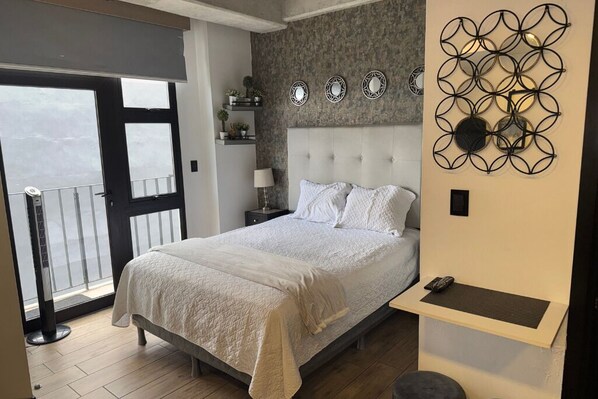 Een slaapkamer met een bed, nachtkastje, lamp, decoratief item aan de muur en uitzicht.