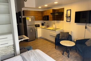 Een knus woongedeelte met kitchenette, een bed, een eettafel en een bank.