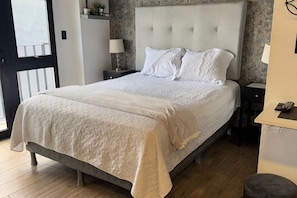 Een slaapkamer met een bed, nachtkastjes en een deur.