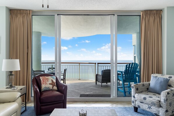Una habitación con vista al mar, un sofá, una silla y una mesa.