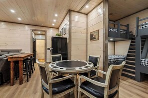 A cozy room with a round table, chairs, a sofa, and a bunk bed. - New | Mtn Views & Modern Luxury | Sleeps 12 | 5 Fireplaces | Pool & Hot Tub (Sevierville)