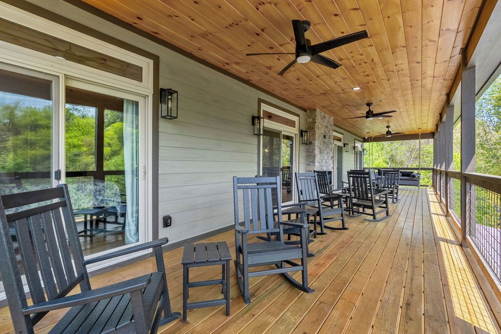 Eine überdachte Veranda mit Holzboden, Sitzgelegenheiten im Freien und Deckenventilatoren.