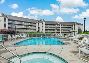A hotel with a swimming pool, multiple balconies, and lounge chairs. - Whispering Pines 634 | 4BR Luxury Condo in the Heart of Pigeon Forge Sleeps 10 (Pigeon Forge)