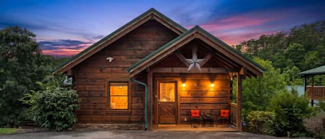 A wooden cabin with a porch, a star decoration, and a view of the surrounding forest.