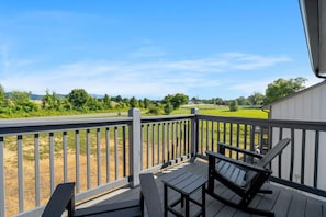A wooden deck with a view of a green field and trees. - Three bedroom, two and a half bathroom cabin in Sevierville near Dollywood (Sevierville)