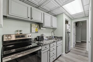A modern kitchen with white cabinetry, a stainless steel refrigerator, and a built-in oven. - Downtown Pigeon Forge Condo| One bedroom, one bathroom| Near The Island (Pigeon Forge)
