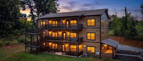 A multi-story wooden building with balconies and outdoor seating, surrounded by greenery.