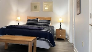 Un dormitorio con cama, mesitas de noche, ventilador de techo y decoración en la pared.