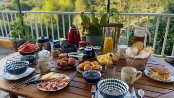 A breakfast table with various food items, utensils, and a potted plant.